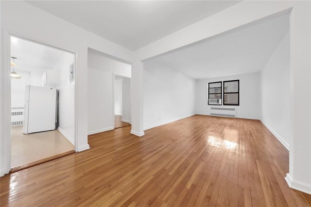 unfurnished living room featuring radiator heating unit and light hardwood / wood-style flooring