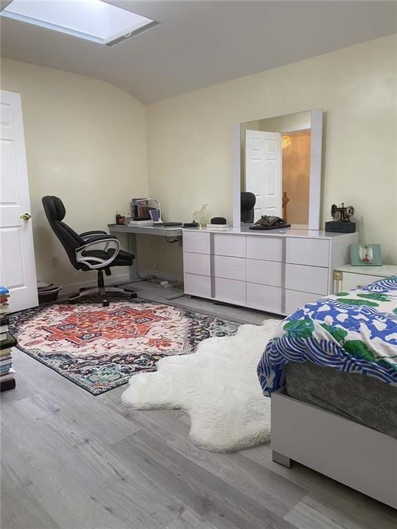 bedroom featuring hardwood / wood-style floors and vaulted ceiling with skylight