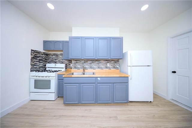 kitchen with tasteful backsplash, white appliances, blue cabinets, and a sink