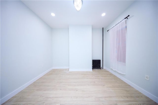 unfurnished room with recessed lighting, radiator, baseboards, and light wood-style floors