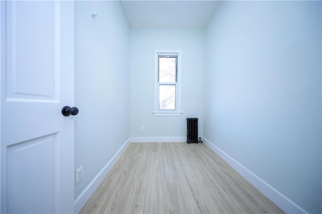 spare room featuring baseboards, light wood-style floors, and radiator heating unit