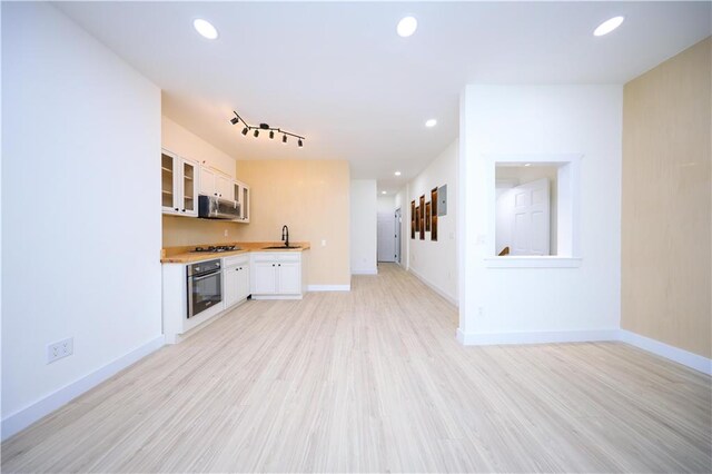 kitchen featuring sink, white cabinets, stainless steel appliances, and light wood-type flooring