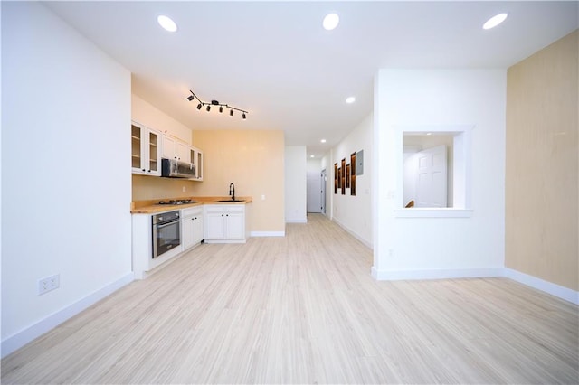 kitchen with stainless steel appliances, light countertops, glass insert cabinets, and recessed lighting