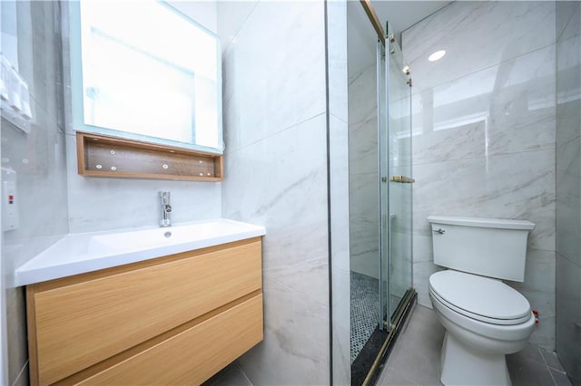 bathroom featuring vanity, a shower with shower door, tile walls, and toilet