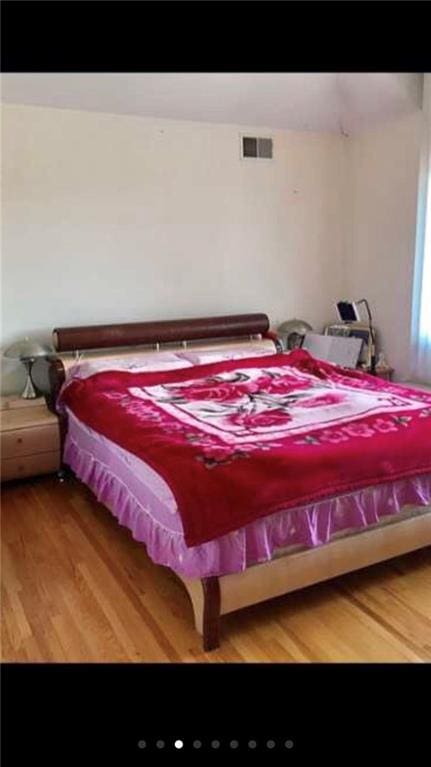 bedroom featuring visible vents and wood finished floors