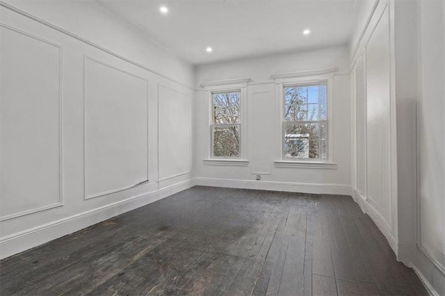 unfurnished room featuring baseboards, dark wood-style flooring, recessed lighting, and a decorative wall