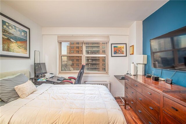 bedroom with wood-type flooring and radiator heating unit