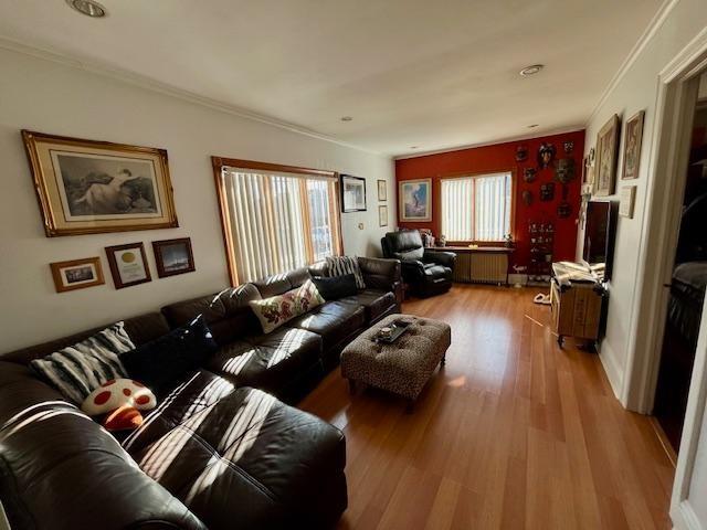 living room featuring radiator, crown molding, and wood-type flooring