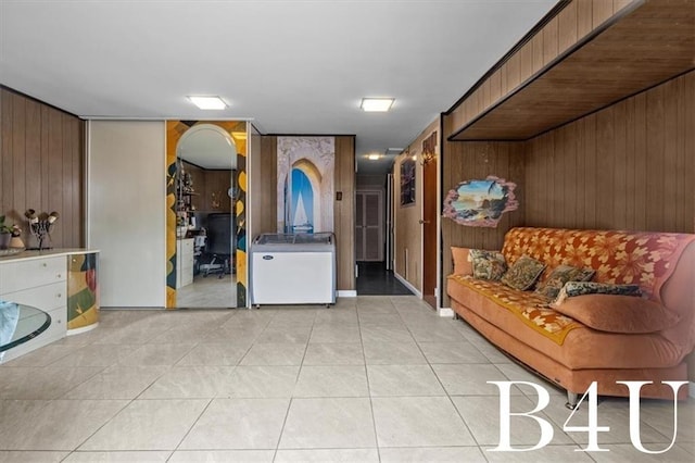 living area featuring wooden walls and light tile patterned floors