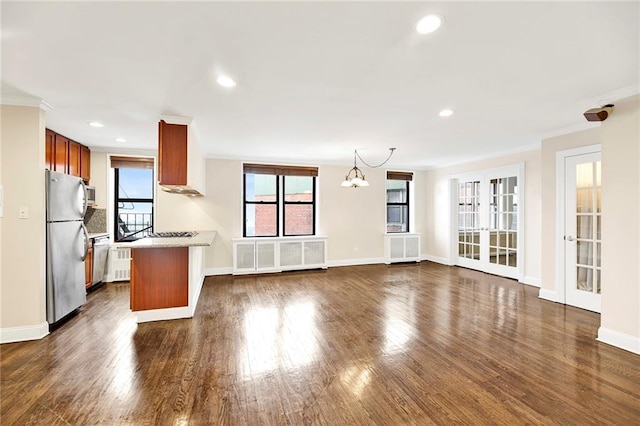 kitchen with radiator heating unit, an inviting chandelier, kitchen peninsula, appliances with stainless steel finishes, and ornamental molding