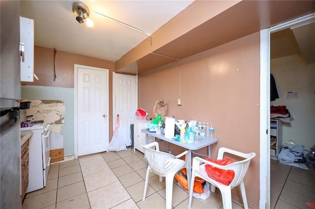 kitchen featuring refrigerator, white cabinets, light tile patterned floors, white stove, and washing machine and dryer