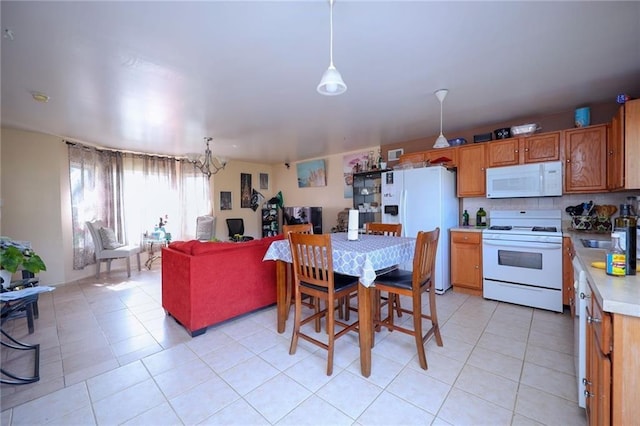 kitchen with pendant lighting, white appliances, an inviting chandelier, and light tile patterned floors