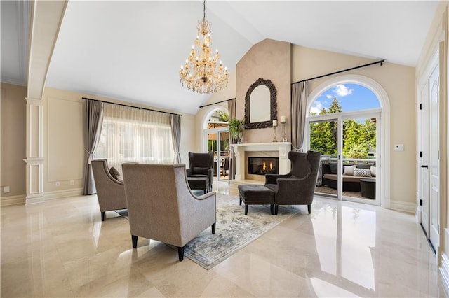 living area featuring a chandelier, high vaulted ceiling, baseboards, marble finish floor, and a glass covered fireplace