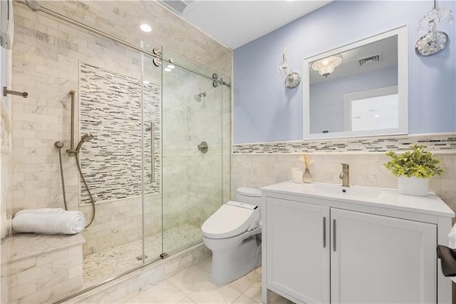 bathroom featuring toilet, vanity, visible vents, tile walls, and a shower stall