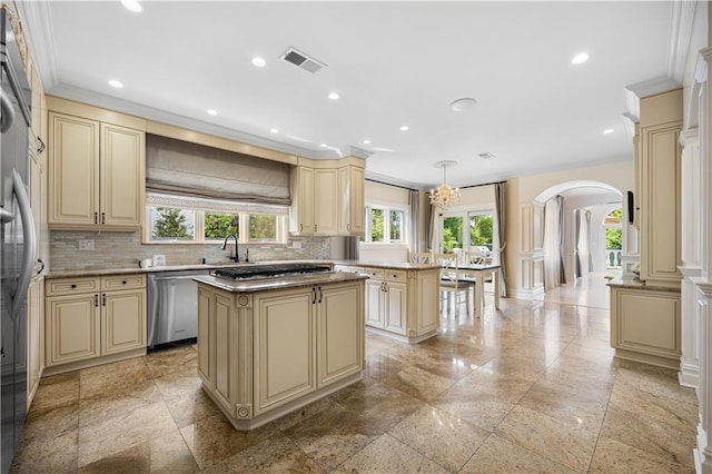 kitchen featuring a center island, cream cabinetry, decorative light fixtures, light countertops, and appliances with stainless steel finishes