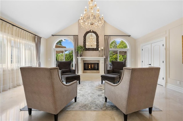 sitting room with high vaulted ceiling, a healthy amount of sunlight, a lit fireplace, and an inviting chandelier