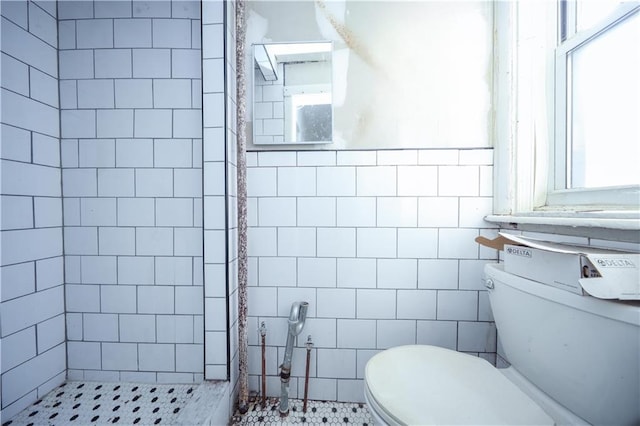 bathroom with tile walls, a wealth of natural light, and toilet