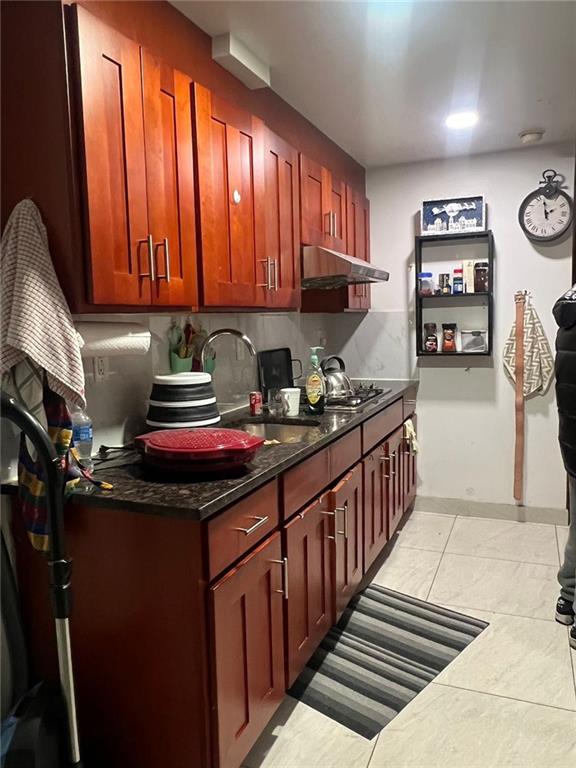 kitchen featuring decorative backsplash, sink, light tile patterned floors, and stainless steel gas cooktop