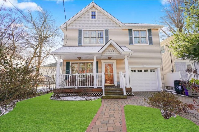 view of front of house featuring covered porch, a garage, and a front lawn