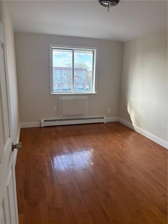 spare room with baseboard heating and hardwood / wood-style flooring