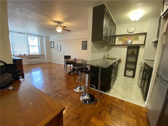 kitchen with parquet flooring, sink, stone countertops, radiator heating unit, and range with gas stovetop