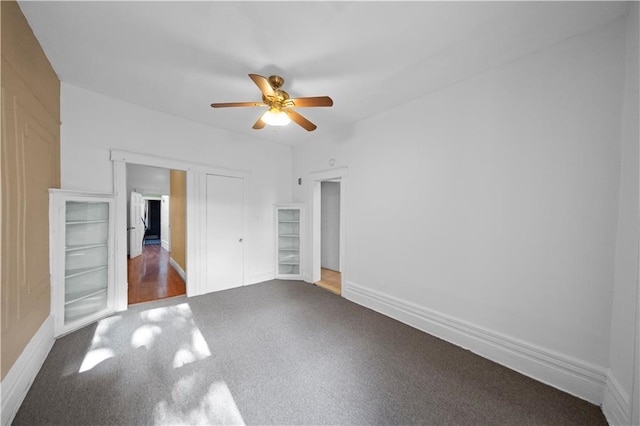 unfurnished bedroom with ceiling fan, carpet, a closet, and baseboards