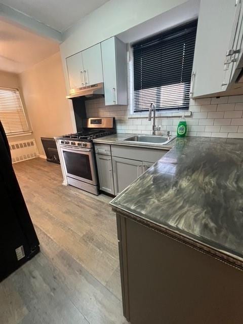 1241 E 98th St, Brooklyn, NY 11236 - kitchen with gas stove, a sink, under cabinet range hood, decorative backsplash, and radiator heating unit