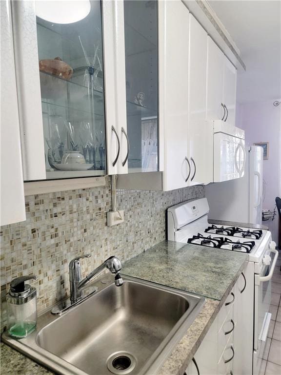 kitchen with white appliances, a sink, white cabinets, and tasteful backsplash