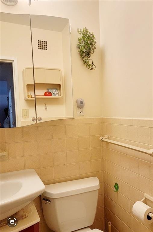 bathroom with tile walls, toilet, and vanity