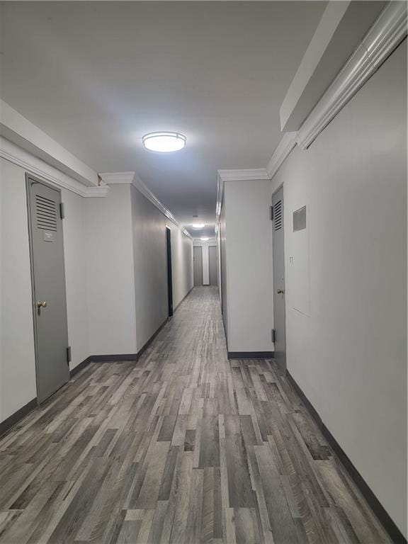 hall featuring wood finished floors, ornamental molding, and baseboards