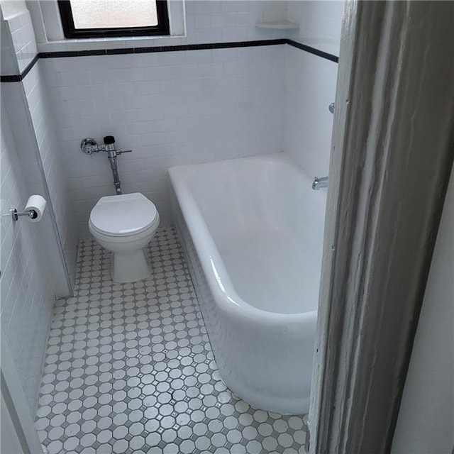 bathroom with a bath, toilet, tile walls, and tile patterned floors