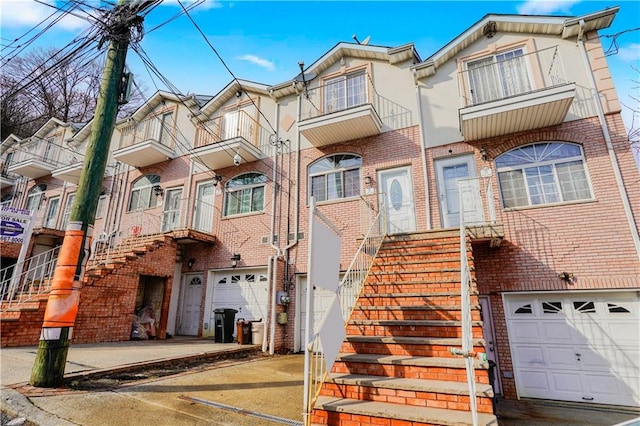 view of front facade featuring stairway, a residential view, brick siding, and an attached garage