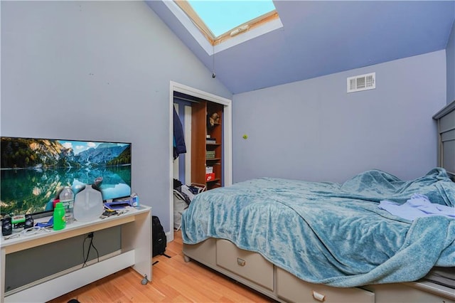 bedroom with visible vents, vaulted ceiling with skylight, and wood finished floors
