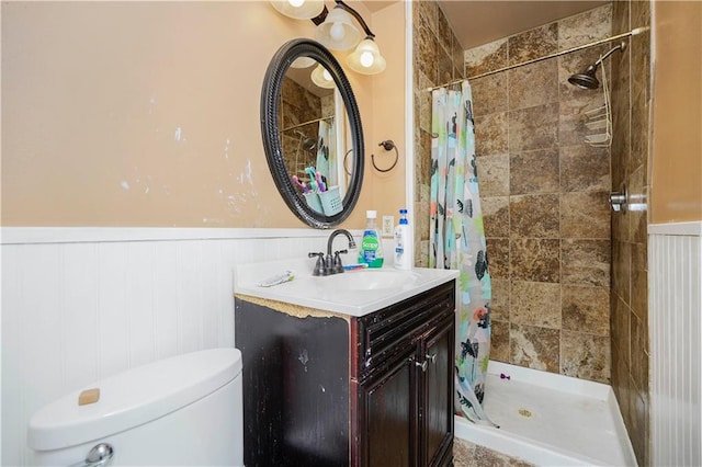 bathroom featuring vanity, toilet, a wainscoted wall, and a stall shower