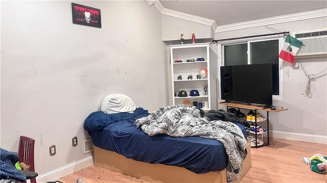 bedroom with a wall unit AC, crown molding, and wood-type flooring