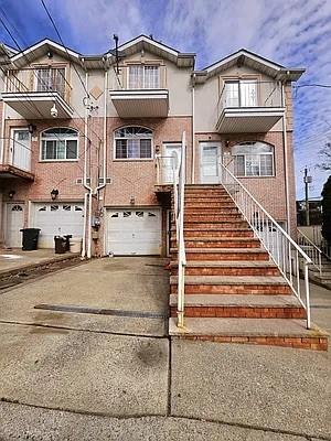 view of front facade featuring a balcony, stairway, a garage, and driveway