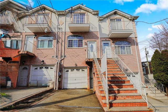 townhome / multi-family property featuring stairs, driveway, brick siding, and an attached garage