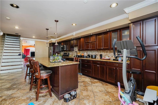 kitchen featuring a breakfast bar area, decorative backsplash, appliances with stainless steel finishes, crown molding, and decorative light fixtures