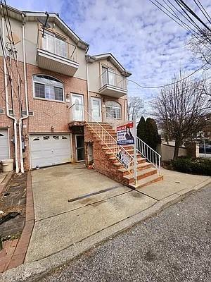 view of front of property with driveway, brick siding, a balcony, and an attached garage