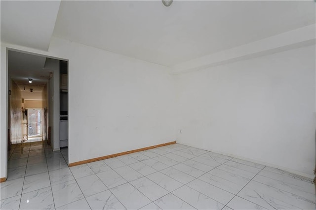 unfurnished room with marble finish floor and baseboards