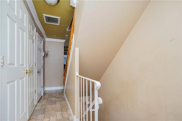 hall featuring stone finish floor, crown molding, an upstairs landing, visible vents, and baseboards