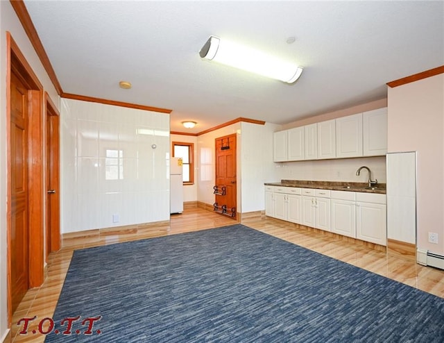 kitchen with white cabinets, white refrigerator, ornamental molding, and sink