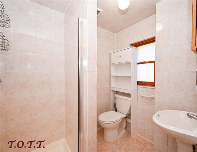 bathroom with sink, tile patterned flooring, an enclosed shower, toilet, and tile walls