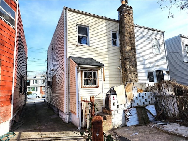 back of house featuring a chimney and fence