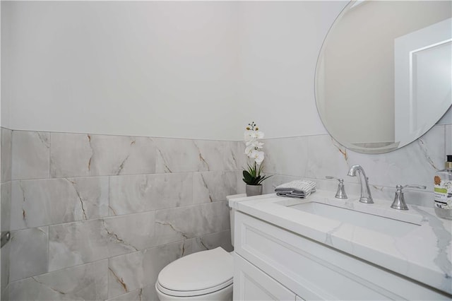 bathroom with toilet, vanity, and tile walls