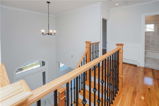 hallway with ornamental molding, light hardwood / wood-style floors, and a notable chandelier