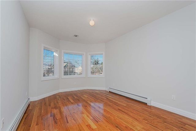 unfurnished room with light wood-type flooring and a baseboard heating unit