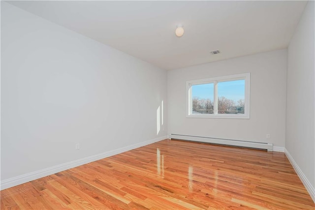 empty room with light hardwood / wood-style floors and a baseboard radiator