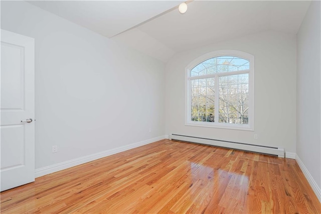 spare room featuring light hardwood / wood-style flooring, vaulted ceiling, and a baseboard radiator