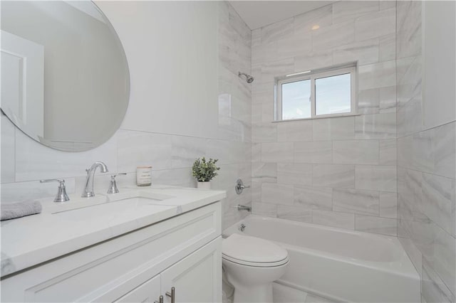 full bathroom featuring toilet, tiled shower / bath combo, vanity, and tile walls